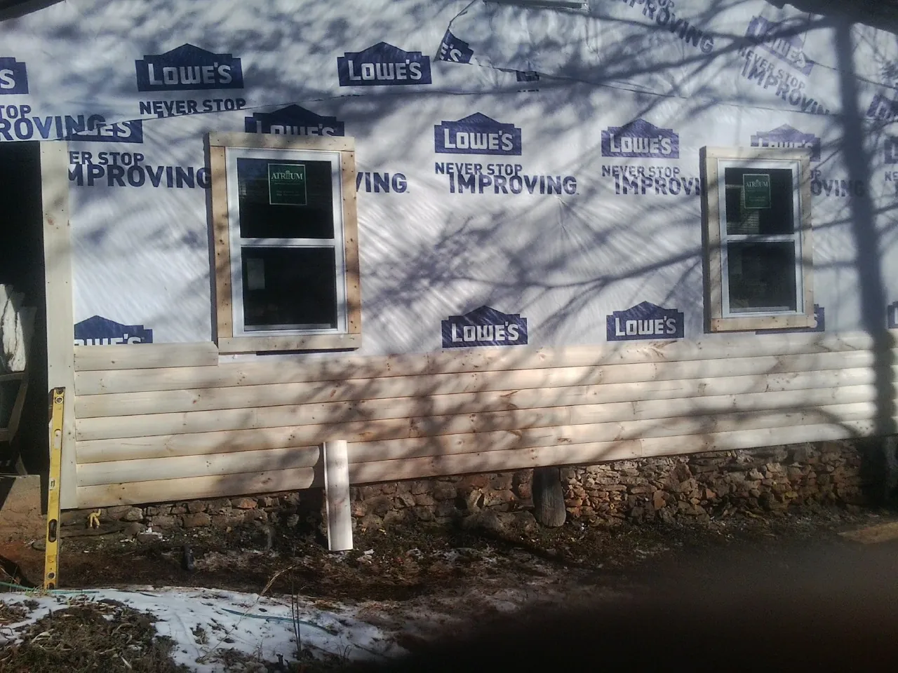 House wrap and new log siding going up on an exterior wall in Verona